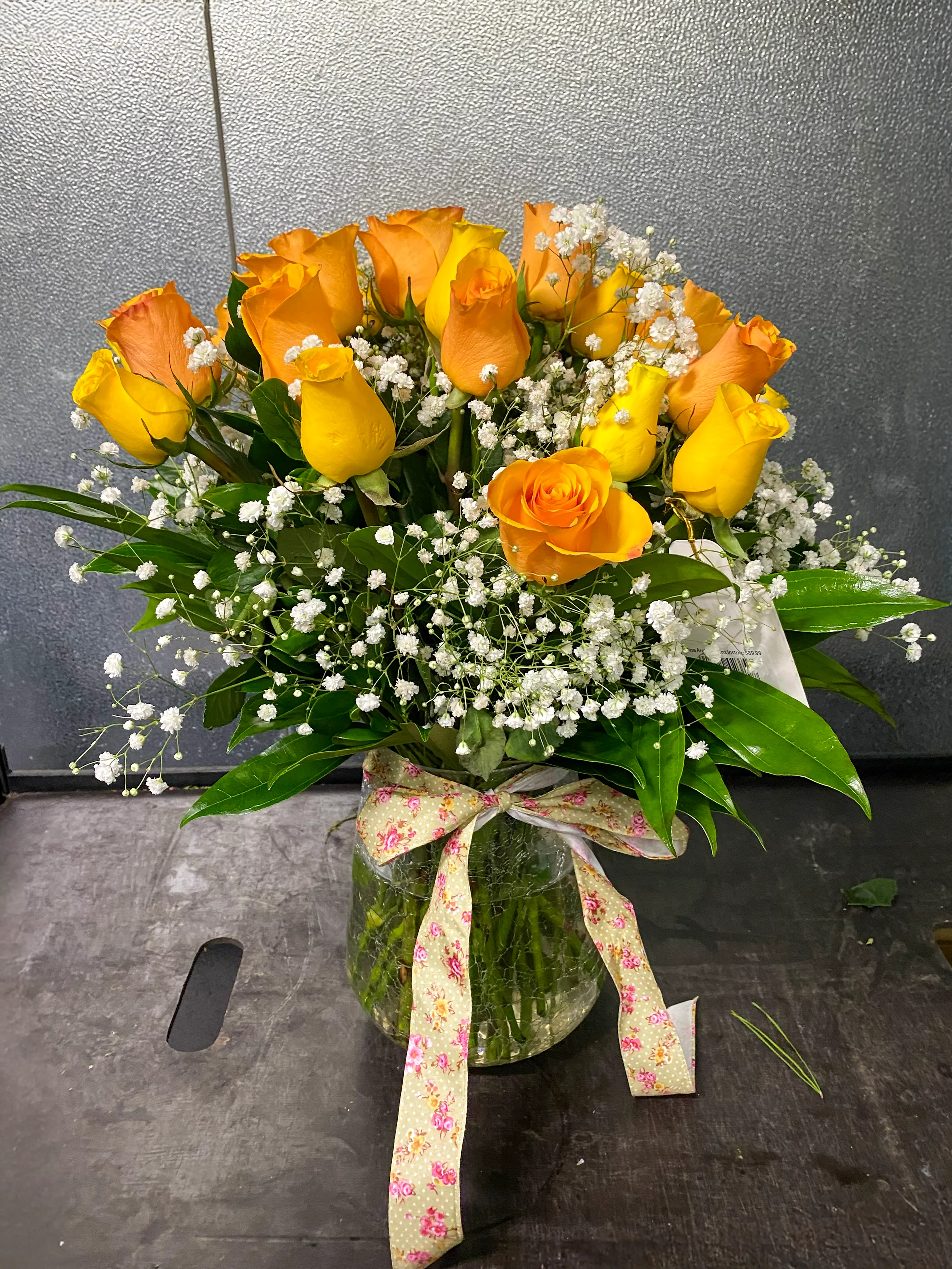 A hand-tied bouquet of yellow and peach roses in a glass vase.